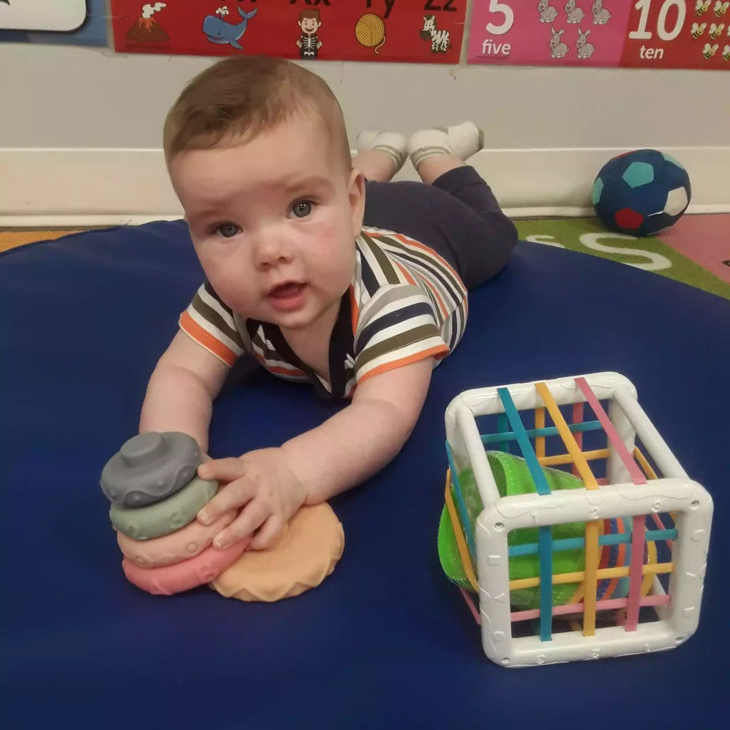 Infant doing tummy time with stacking rings and sensory toys