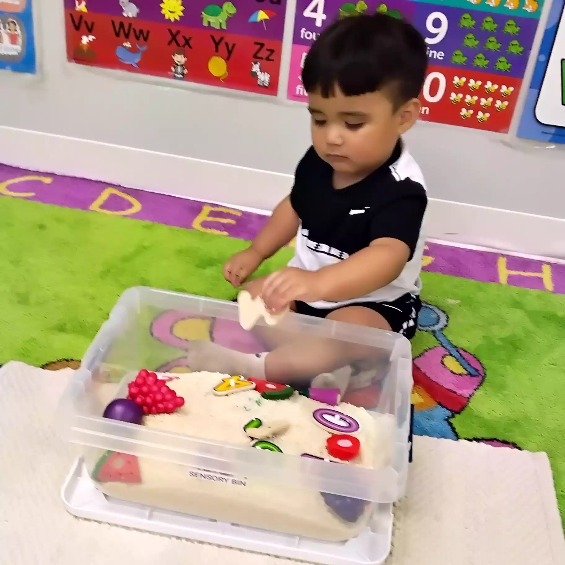 Pinebrook Pre-K Student Exploring Alphabet Sensory Bin - Pinebrook- Preschool - Pinebrook- Preschool Child playing with sensory bin at Pinebrook Montessori