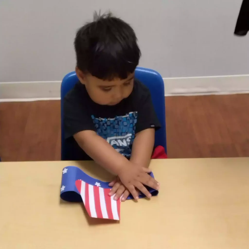 Teacher helping student with handprint craft at Pinebrook Montessori