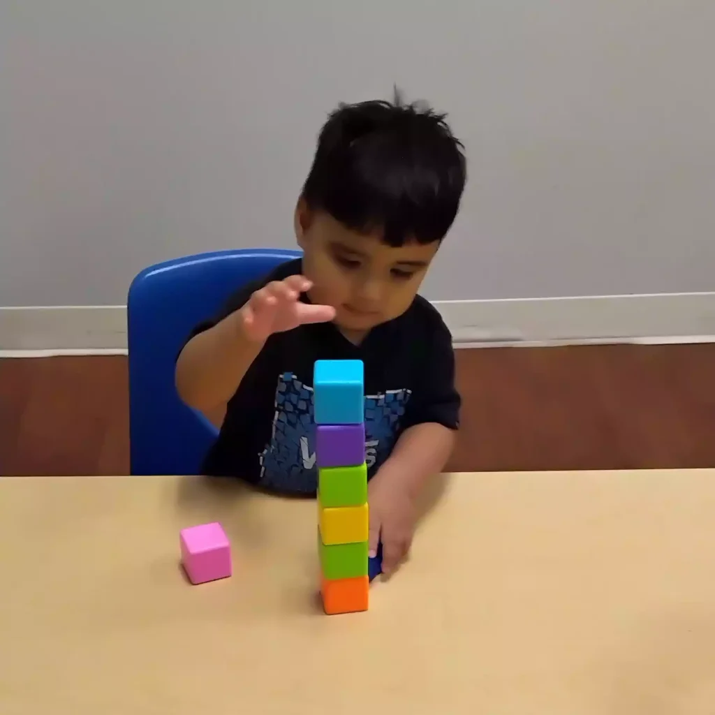 Student stacking colorful toy blocks at Pinebrook Montessori