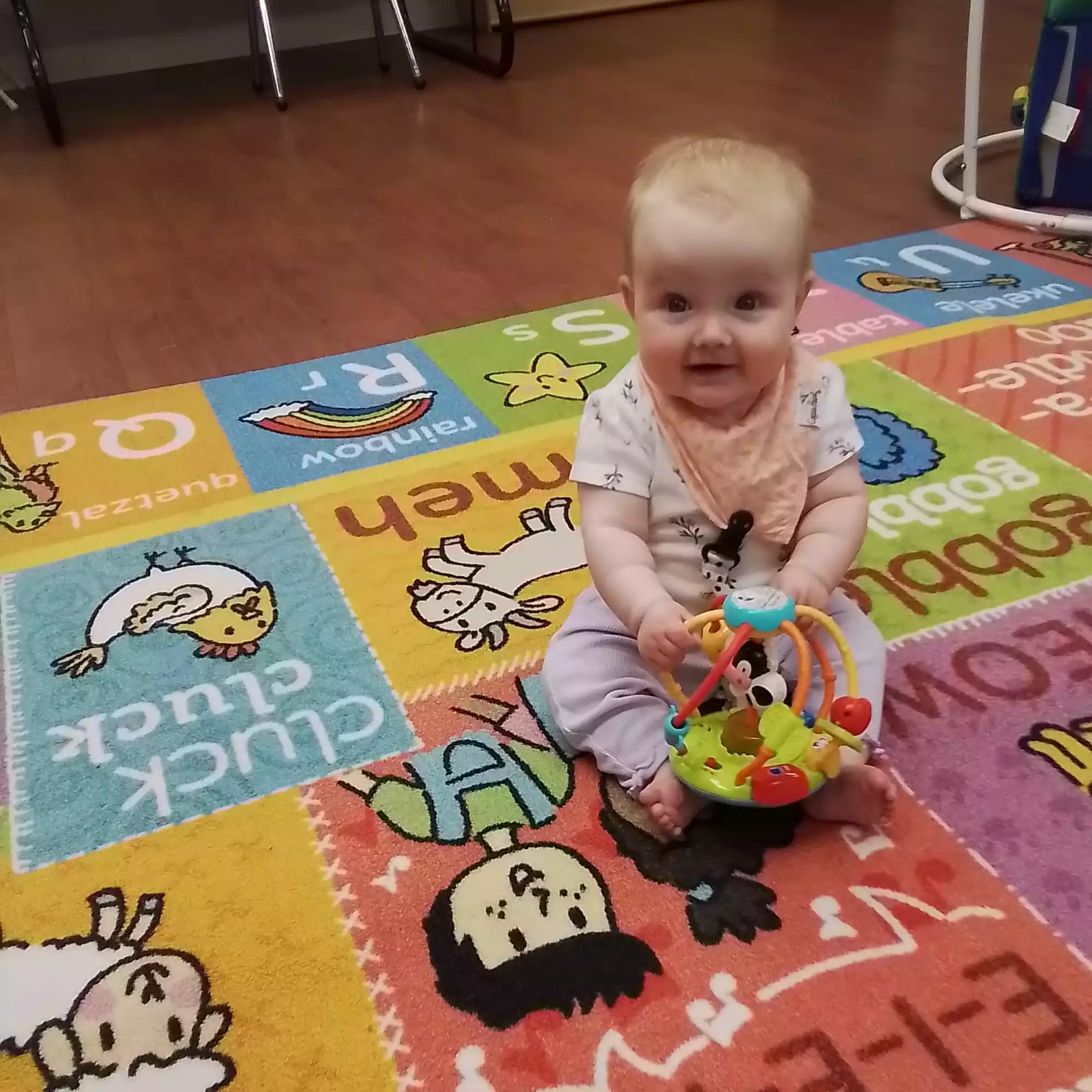 Infant Sitting on Play Mat Exploring Activity Rattle - Pinebrook- Preschool - Pinebrook- Preschool Baby sitting on colorful play mat with interactive sensory rattle in infant program