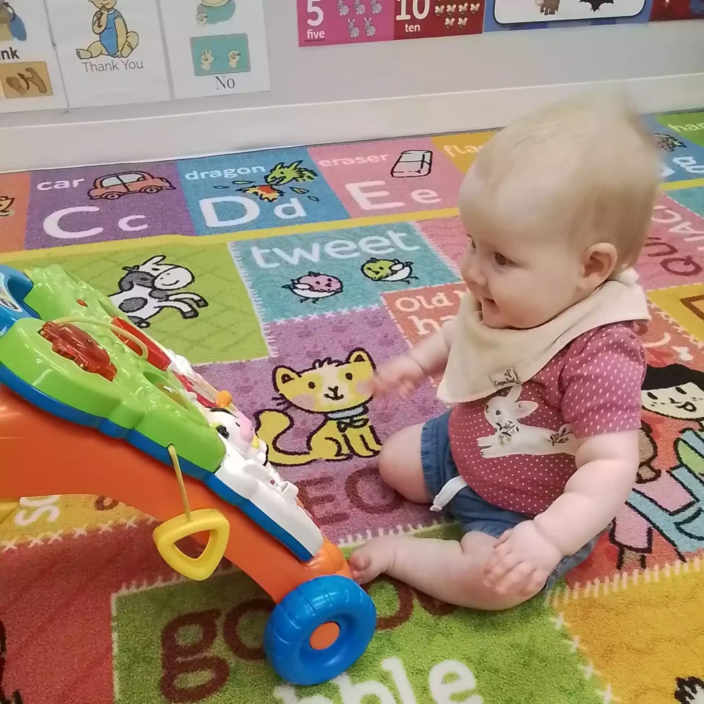 Baby exploring soft foam climber during floor play in infant program