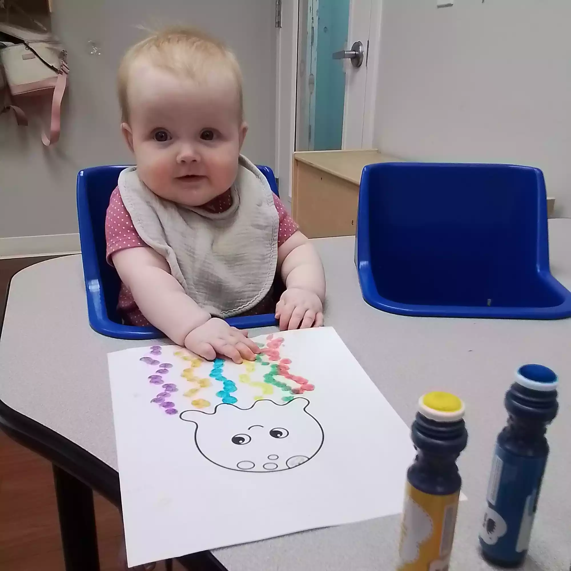 Infant Decorating Jellyfish Artwork with Dab Marker - Pinebrook- Preschool - Pinebrook- Preschool Infant creating jellyfish dot marker artwork at activity table in classroom
