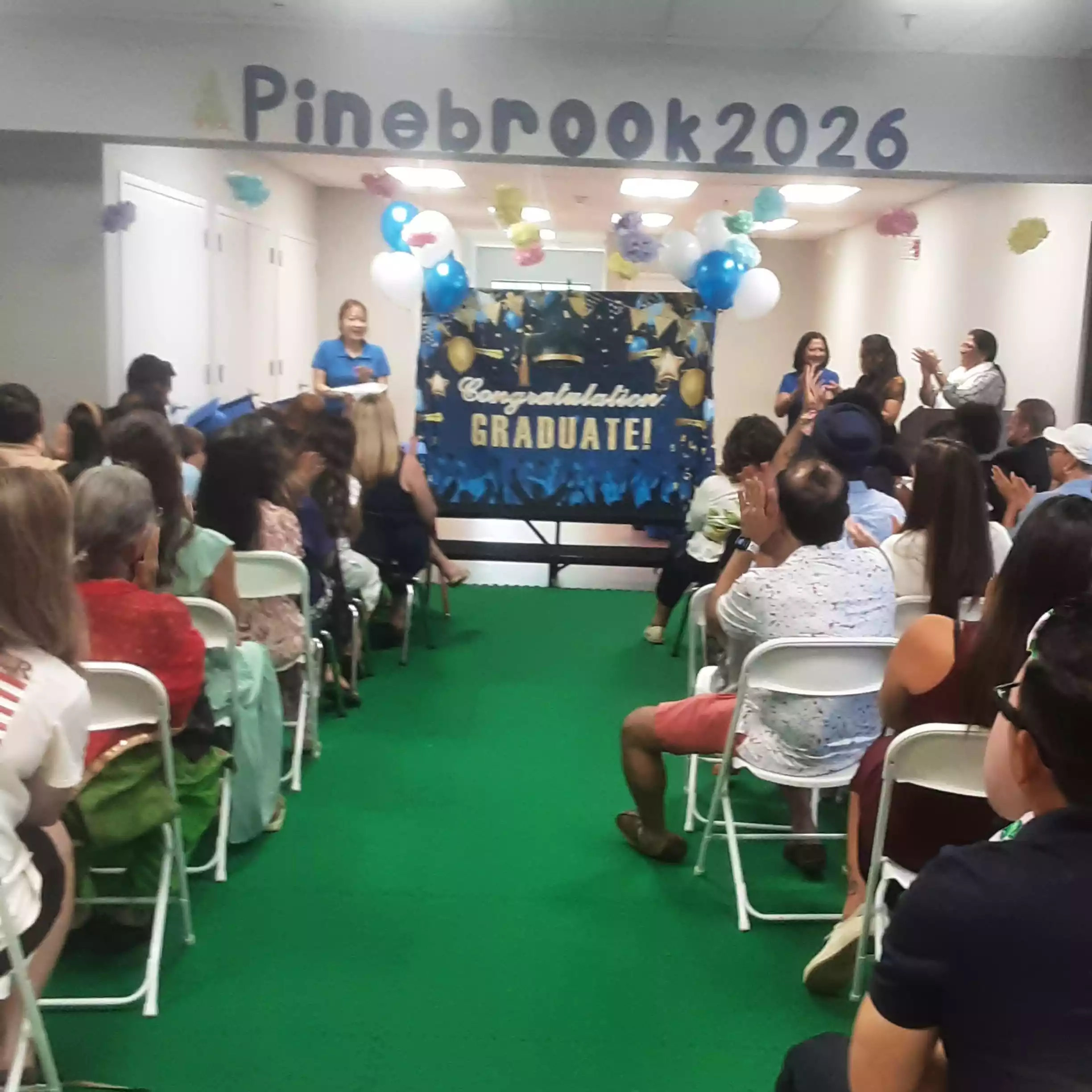 Pinebrook 2026 Graduation Stage and Audience - Pinebrook- Preschool - Pinebrook- Preschool Parents seated watching Pinebrook 2026 pre-K graduation ceremony