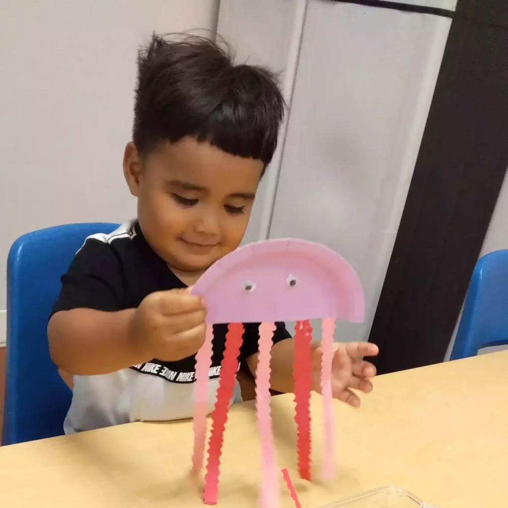 Child showing completed paper jellyfish craft at Pinebrook Montessori